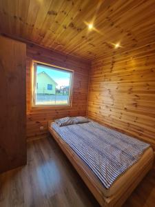 Cama en habitación de madera con ventana en Domki Róża Bobolin en Bobolin