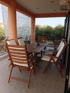 patio z drewnianym stołem i krzesłami na ganku w obiekcie Margaret's House w mieście Kefalonia