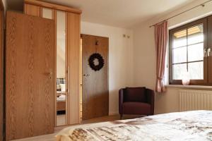 1 dormitorio con 1 cama, 1 silla y 1 ventana en Das Waldseechalet Märchenhafter Waldseeblick - moderne Wohnung mit Infrarotsauna, en Hasselfelde