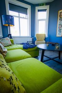 una sala de estar con 2 sofás verdes y una mesa. en Guesthouse Holl, en Vestmannaeyjar