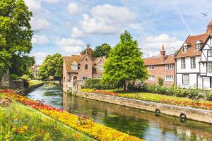 a river in a town with houses and flowers at Entire Flat, Canterbury Centre - Free Parking in Kent