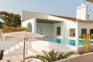Casa blanca con piscina y sombrilla en The Green House Alentejo by Santiago de Alfama, en Vila Nova da Baronia