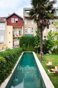 a swimming pool in a yard with a palm tree and buildings at Hotel Tipografia do Conto by Casa do Conto in Porto