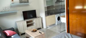 pequeña sala de estar con TV y cocina en Estudio Fibes-Lux Sevilla, en Sevilla