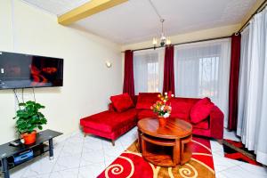 Peace of Mind Suites في عنتيبي: غرفة معيشة مع أريكة حمراء وطاولة