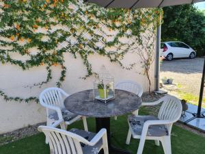 una mesa y cuatro sillas bajo una sombrilla en Le Coq en Repos, en Saint-Sylvestre-sur-Lot
