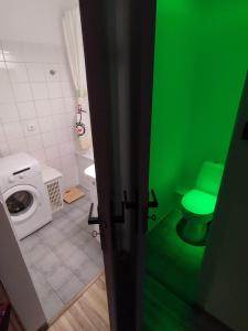a green bathroom with a toilet and a washing machine at Chill Studio in Łódź