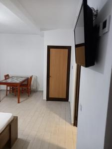 a room with a door and a table and a television at CAZARE Centrum in Curtea de Argeş