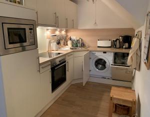 a kitchen with white cabinets and a washer and dryer at Ferienwohnung Apfelrose in Oldsum +15 photos