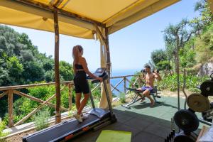 a woman standing on a treadmill in a gym with a view of the ocean at YourHome - Relais Casa degli Angeli in Positano
