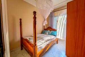 a bedroom with a canopy bed with a window at Peace of Mind Suites in Entebbe