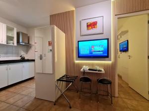 a kitchen with two bar stools and a tv on the wall at Belle Arti Pousada in Florianópolis