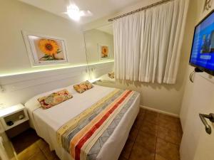 a small bedroom with a bed and a television at Belle Arti Pousada in Florianópolis +42 photos