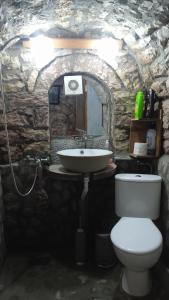 uma casa de banho com um lavatório e um WC numa caverna em Karafil Guesthouse em Gjirokastër