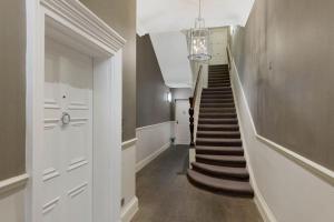 a hallway with a staircase with a chandelier at Wonderful Knightsbridge Apartment by Harrods in London
