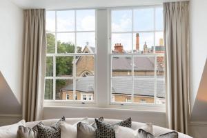 a white couch sitting in front of a large window at Wonderful Knightsbridge Apartment by Harrods in London