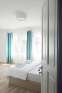 a bedroom with a bed with white sheets and blue curtains at Alicante Hotel - Adult Only in Bozcaada