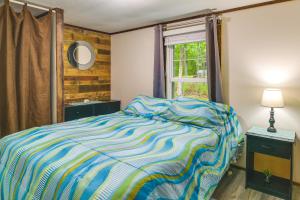 a bedroom with a bed with a striped comforter and a window at New Concord Vacation Rental Near Kentucky Lake in New Concord