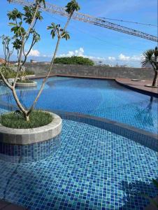 una piscina con suelo de baldosa azul y una palmera en Citra Plaza Nagoya, en Nagoya