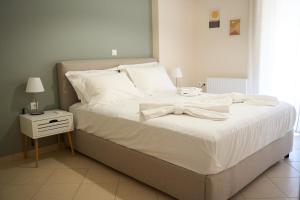 a bed with white sheets and a bow on it at ILOS APARTMENT in Nafplio