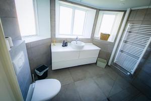 a bathroom with a white sink and two windows at Guesthouse Holl in Vestmannaeyjar