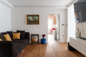 uma sala de estar com um sofá preto e paredes brancas em Fantabulous Upper-Town Condo em Zagreb