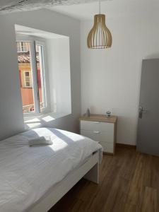 a white bedroom with a bed and a window at Grand appartement hyper centre Grasse in Grasse