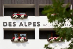 a white building with flowers in the windows at Hotel Des Alpes in La Villa +43 photos