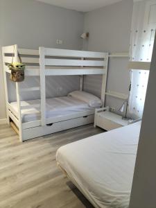 薩卡羅的住宿－Vilar d'Aro Apartment，卧室配有两张双层床和一张白色床。
