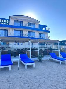 a building on the beach with blue chairs in front at KIR House On The Beach in Eforie Nord