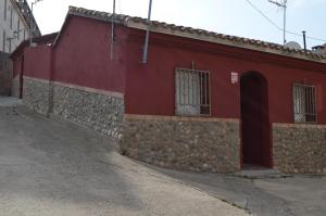 een rood gebouw met een stenen muur naast een straat bij Casa el Susurro in Villamediana de Iregua