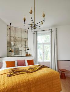 ein Schlafzimmer mit einem großen gelben Bett mit einem Kronleuchter in der Unterkunft Villa Chez les Amis - Adults only in Balatonszepezd