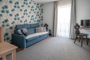 ein Wohnzimmer mit einer blauen Couch und Blumentapete in der Unterkunft Guesthause Pr' Jozef in Bled