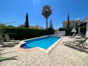 a swimming pool in a yard with chairs and a house at Villa Tamara with Private Pool in Peyia