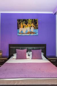 una camera da letto con un letto con pareti viola e una foto di uccelli di Pensiunea Aura a Murighiol