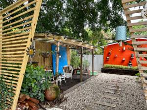 a garden with a wooden pergola and a red house at Flora's Garden Apartment/Studio in North Miami