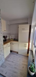 a kitchen with white cabinets and a white refrigerator at Break in Kudensee