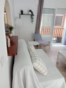 un letto bianco con cuscini in soggiorno di Apartamento en Fuengirola a Fuengirola