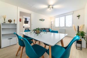 a dining room with a white table and blue chairs at Blue sky cottage near CDG airport in Le Mesnil-Amelot