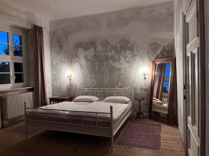 a bedroom with a bed and a wall with a mirror at Gut Manderow an der Ostsee in Hohenkirchen