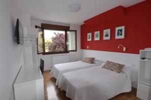 a bedroom with two beds and a red wall at B&B Zaldu in Estella