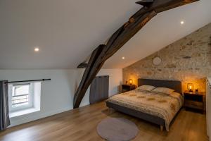 ein Schlafzimmer mit einem Bett und einer Steinmauer in der Unterkunft Le Loft Gîte de Dordogne in Mussidan