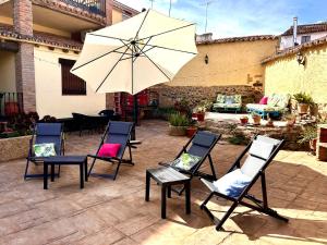 un grupo de sillas y una sombrilla en un patio en La Casa del Marqués, en Logrosán