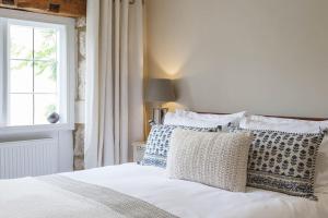 a bedroom with a bed with pillows and a window at Stylish Painswick Getaway in Painswick