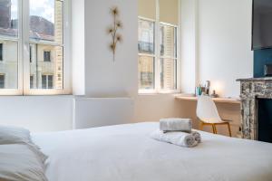 een witte slaapkamer met een bed met handdoeken erop bij NANCY HYPERCENTRE 25 rue Saint Georges, 2e étage in Nancy