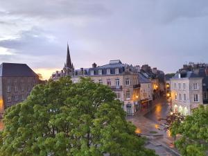 una vista de una ciudad al atardecer con una iglesia en Hôtel Le Vauban, en Carentan