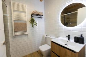 een badkamer met een toilet, een wastafel en een spiegel bij Apartamentos Gurugú in Ribadeo