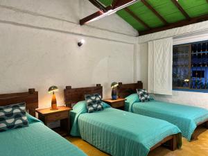 una camera con tre letti con lenzuola verdi e una finestra di Casa El Tesorito a La Tebaida