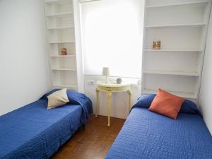 a bedroom with two beds and a table with a window at Apartamento con vistas a la Giralda. in Seville