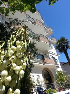 een wit gebouw met een boom ervoor bij Ilios Residence in Lido di Jesolo